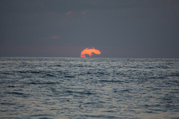 sun touching the horizon in the sea