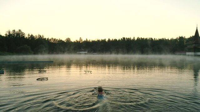 Aerial drone shot of wonderful Lake H&eacute;v&iacute;z at sunrise with woman swimming in the water