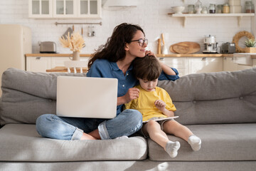 Loving mother businesswoman happy to work from home on coronavirus quarantine hug small son playing...