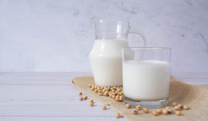 Close up tasty organic homemade soy milk in glass and soybean or soya beans in glass bowl on a wooden table background.Soy milk is a beverage made from soy.Alternative milk and healthy concept.