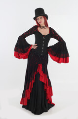 full length portrait of red haired woman wearing long black gothic vampire gown. standing pose on white studio background