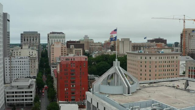 America USA and Virginia State flags fly high atop building in downtown urban city. Aerial drone view.