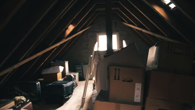 Pan Shot of an old interior vintage gable roof cluttered with boxes and cartons and the bright sun shining through the window