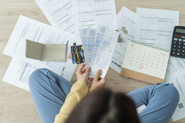 Top view owe asian woman, female sitting on floor stressed and confused by calculate expense from invoice or bill, have no money to pay, mortgage or loan. Debt, bankruptcy or bankrupt concept.
