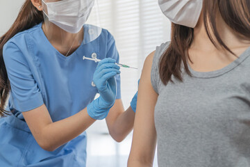 Covid-19,coronavirus hand of young woman nurse,doctor giving syringe vaccine, inject shot to asian...