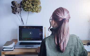 ノートパソコンで動画再生する女性の後ろ姿のテクノロジーイメージ
