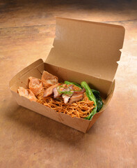 deep fried wanton dumpling char siew dry noodle mee and vegetables in bento box packaging for take...