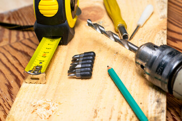 measuring tape measure drill with a drill pencil screwdrivers board on a wooden workbench