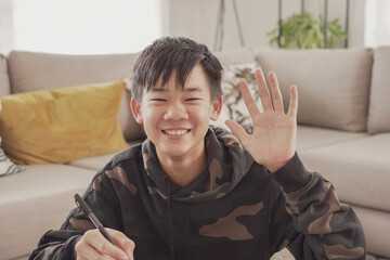 POV Portrait of Asian preteen teen boy making video calling at home, using webcam zoom online virtual class , social distancing, homeschooling, remotely  learning during covid pandemic