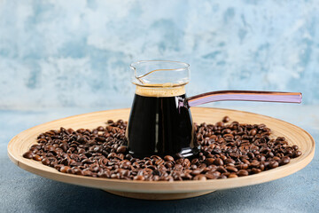 Pot with delicious turkish coffee and plate with beans on color background