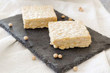 Tempeh natural on a black slate plate. Tempeh is a vegetable protein made from soybean-1