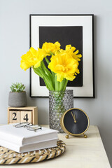 Alarm clock, vase with beautiful flowers and books on table