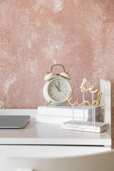 Alarm clock with books and decor on table near color wall