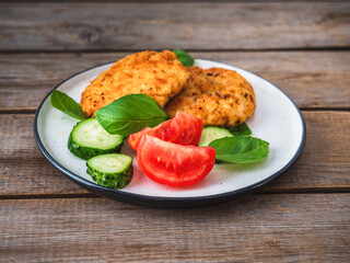 Chicken cutlets with vegetables, cucumber and tomatoes and basil on a light plate