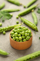 Green peas in wooden bowl on grey background