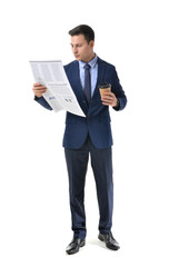 Young businessman with cup of coffee reading newspaper on white background