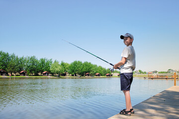 Young boy enjoys fishing at summer sunny day