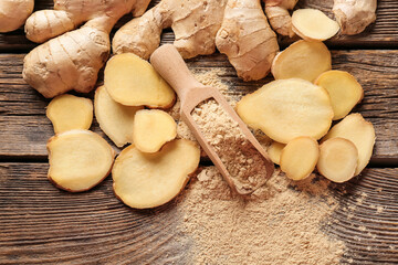 Scoop with ground ginger and roots on wooden table