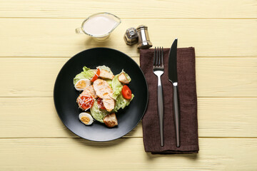 Plate with delicious Caesar salad on color wooden background