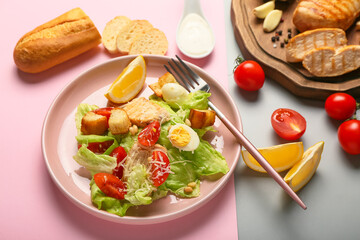 Plate of tasty Caesar salad and ingredients on color background