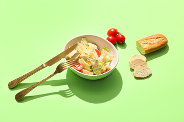 Bowl with Caesar salad on color background