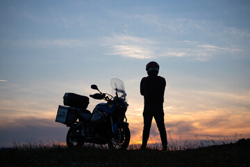 Man on his motorbike admiring sunset - summer road trip