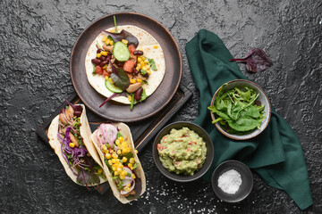 Composition with tacos and tasty guacamole in bowl on dark background