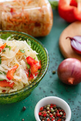 Bowl with tasty sauerkraut and ingredients on color background
