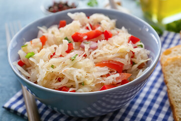 Bowl with tasty sauerkraut on color background