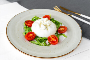 Salad with burrata cheese and cherry tomatoes on white wooden background