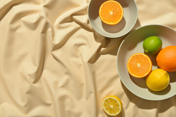 Bowls with healthy citrus fruits on light fabric background