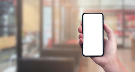 Blank screen of Mobile phone with hand holding phone on Soft blurry Supermarket store background. of free space for copy and Branding.