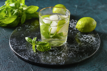 Glass of lemonade with basil on dark background