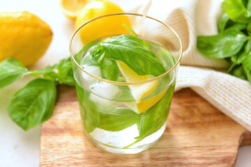 Glass of lemonade with basil on light background