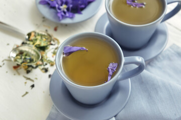 Obraz na płótnie Canvas Cups with tasty floral tea on light wooden background
