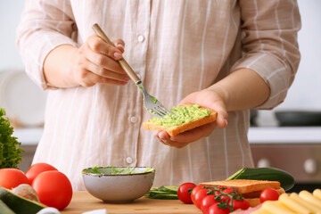 Woman preparing tasty sandwich in kitchen