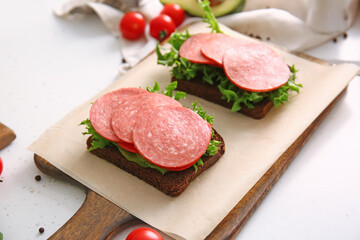 Preparing of tasty sandwiches on light background