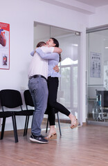 Excited husband hugging wife after receiving good news from doctor in hospital waiting area. Happy young couple for good clinical result screaming in reception area