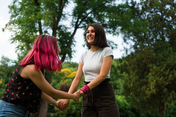 Fototapeta premium Two young women are dancing in the park and enjoying every moment. They are smiling from ear to ear.