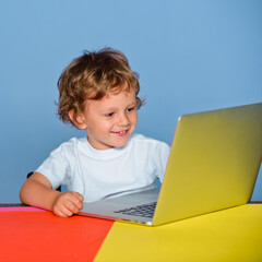 Little boy pupil with happy face expression near laptop, school concept. Kid with a notebook. Closeup portrait of clever child boy pupil with laptop. Child from elementary school.