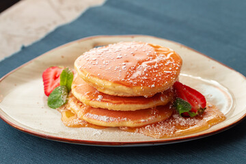 Pancakes with strawberry and maple syrup on table