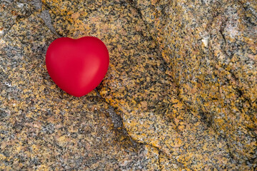 Fototapeta premium Red heart symbol of love on a rough stone surface. Abstract Saint Valentine background.