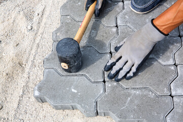 a worker laying paving slabs with a mallet