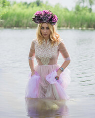 Beautiful girl in wreath of flowers at lake. Portrait of Young beautiful woman. Young pagan girl...