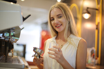 Close-up of Beautiful woman using coffee machine in kitchen