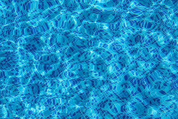 Ripples of swimming pool with mosaic bottom. Sun reflection on the blue clear water 