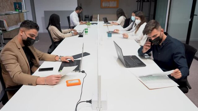 Group of colleagues sitting at table in office and working