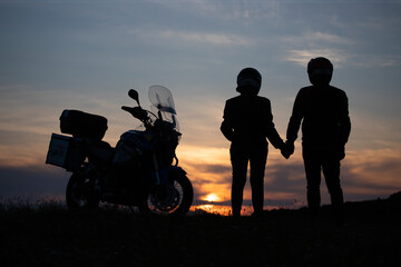 Obraz na płótnie Canvas Silhouette of lover couple in sunset with motorcycle in sunset.