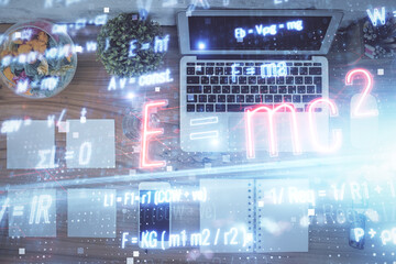 Physics and math theme hologram with formula drawings over computer on the desktop background. Top view. Multi exposure. Concept of education.