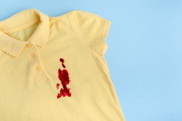 Blood stains on a yellow t-shirt. space for text. isolated on blue background